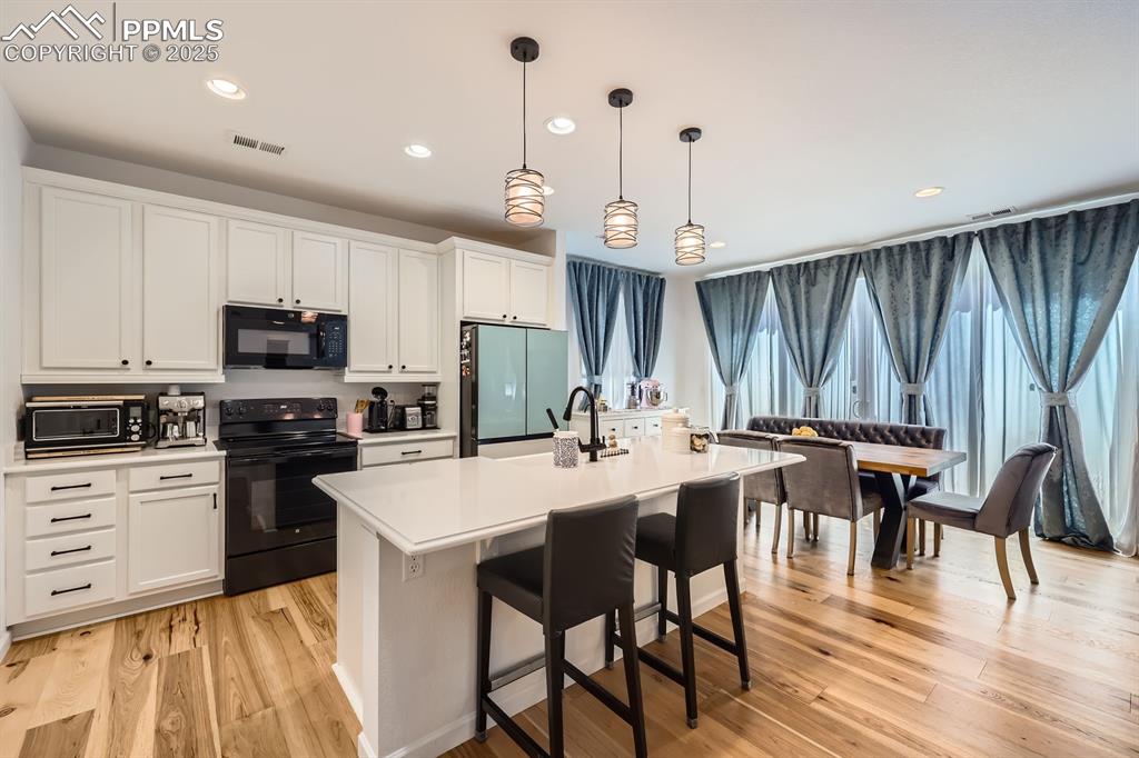 Image 11 of 28: Kitchen featuring black appliances, light countertops, a center island with