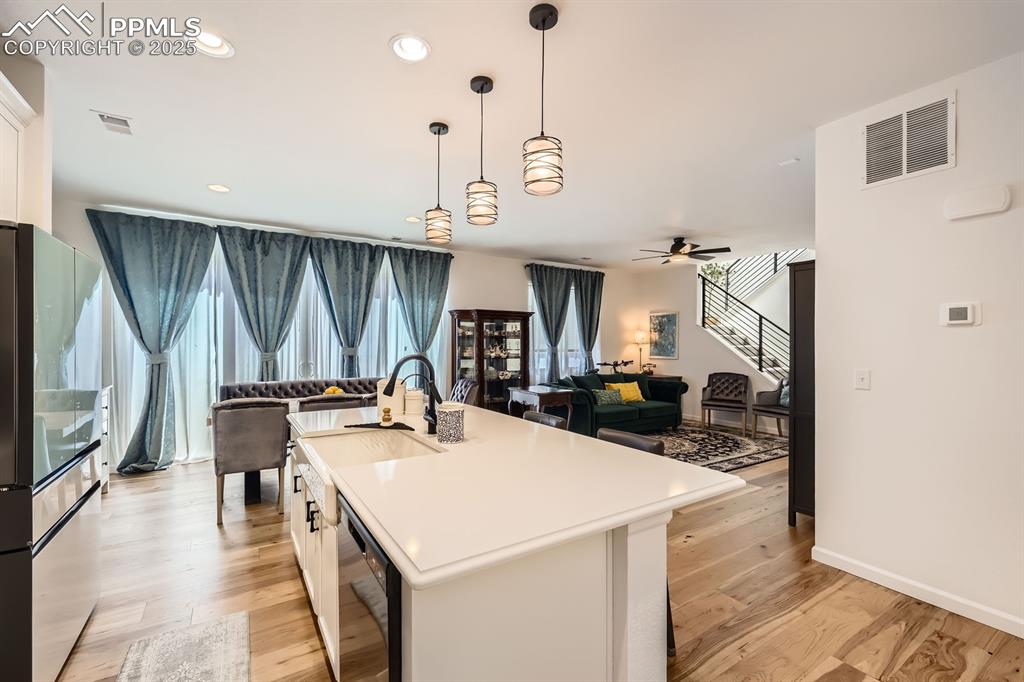 Image 12 of 28: Kitchen featuring dishwasher, white cabinetry, open floor plan, ceiling fan