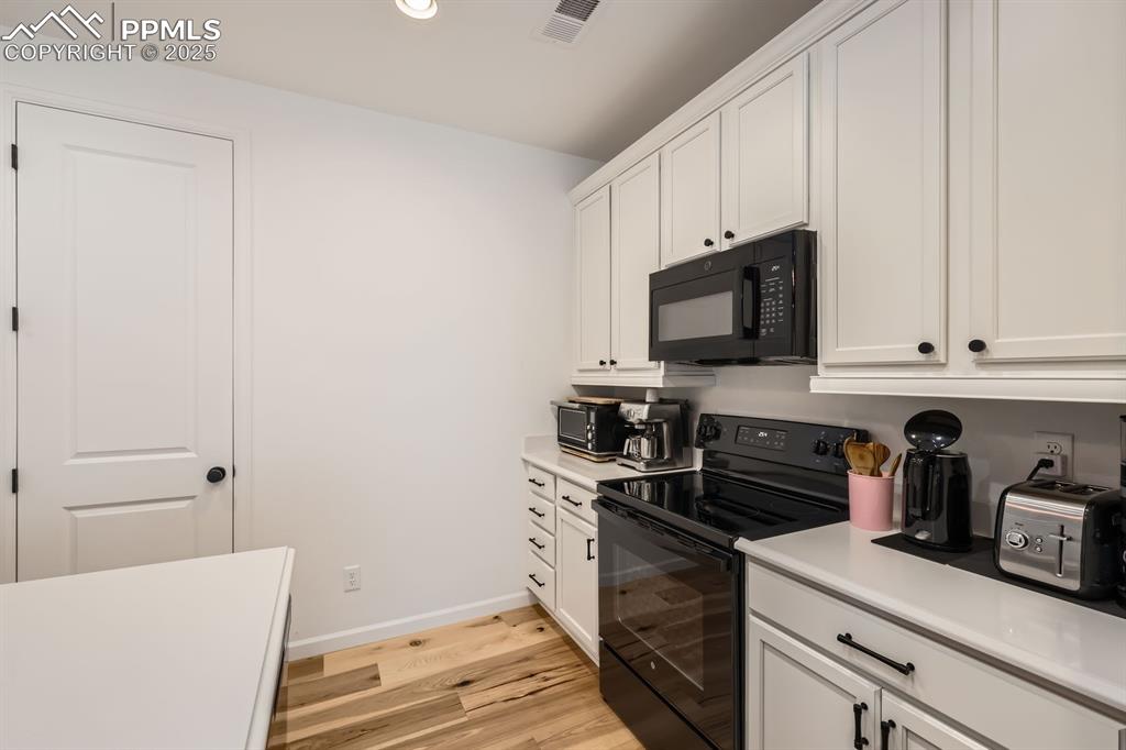 Image 13 of 28: Kitchen featuring black appliances, light wood finished floors, light count