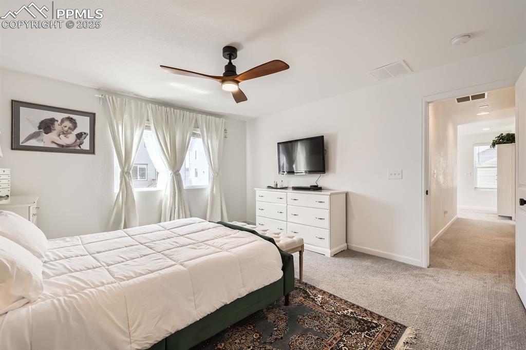 Image 18 of 28: Bedroom featuring multiple windows, light carpet, and ceiling fan