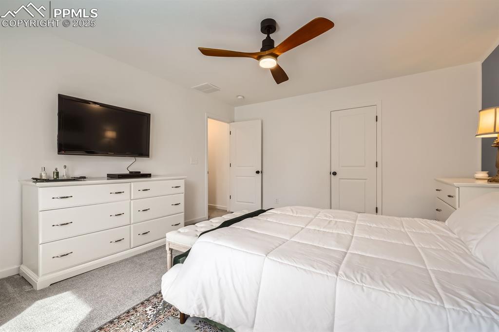 Image 21 of 28: Bedroom with light carpet and a ceiling fan