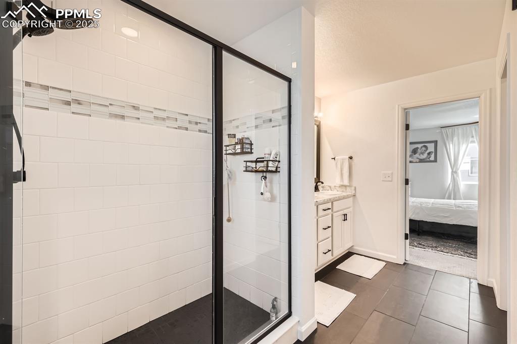 Image 23 of 28: Ensuite bathroom with a stall shower, vanity, and tile patterned flooring