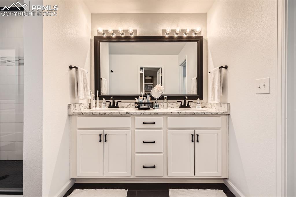 Image 24 of 28: Bathroom with double vanity and tiled shower