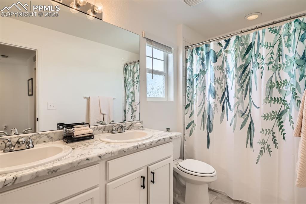 Image 28 of 28: Bathroom featuring double vanity and curtained shower