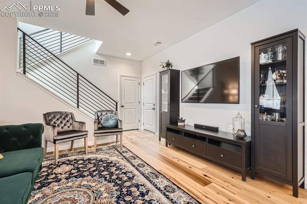 Image 7 of 28: Living area featuring light wood-style flooring, stairs, ceiling fan, and r