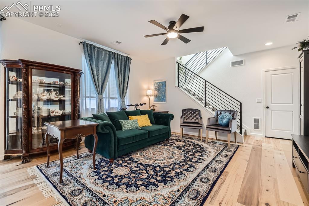 Image 8 of 28: Living room featuring ceiling fan, stairway, light wood finished floors, an