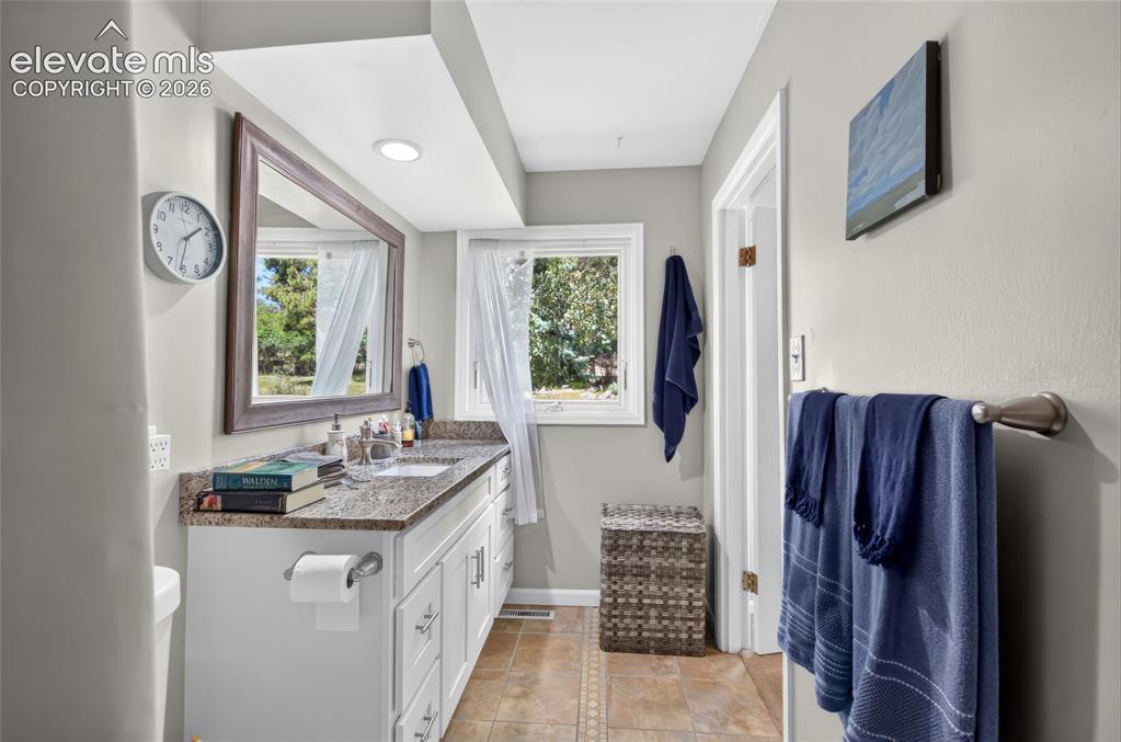 Image 18 of 43: Vanity with a granite-style countertop, undermount sink, and shaker-style c