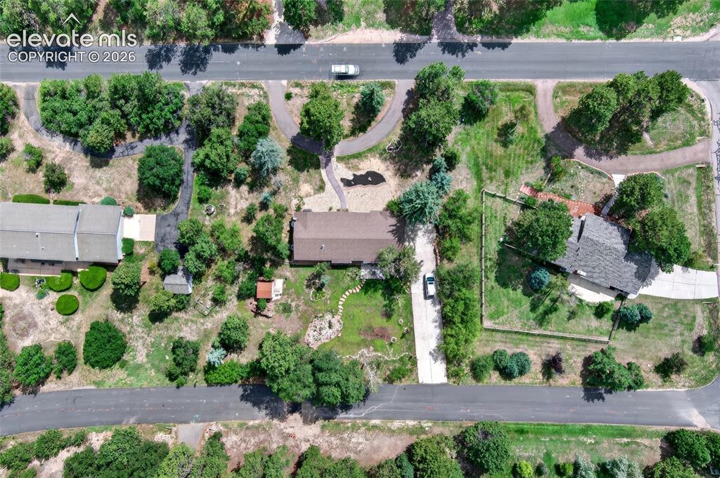 Image 38 of 43: Expansive property featuring mature trees, paved driveways, a shingled roof