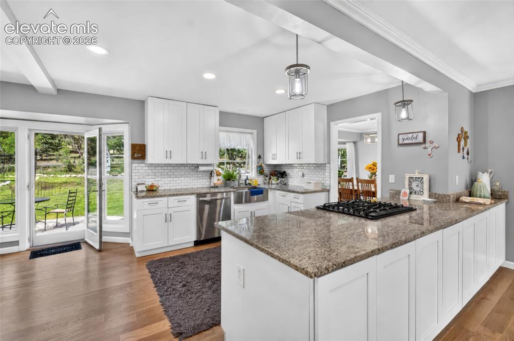 Image 6 of 43: Kitchen featuring white cabinetry, a built-in cooktop, stainless steel dish