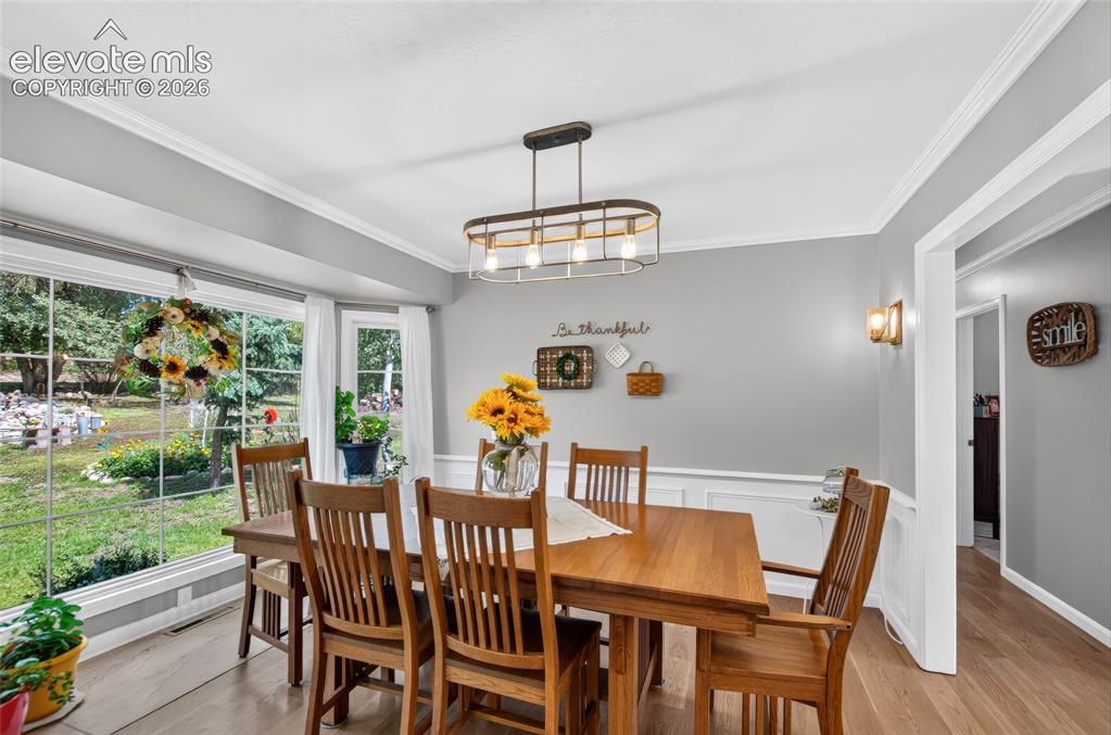 Image 8 of 43: Bright dining space with a large bay window, crown molding, and wainscoting