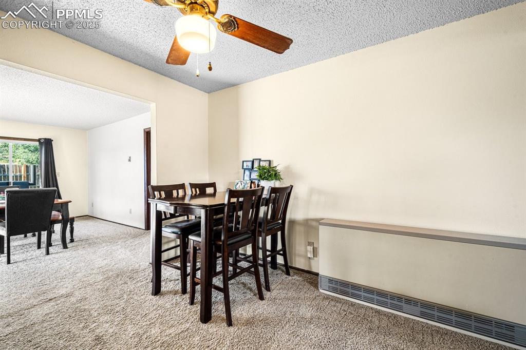 Image 11 of 38: Dining space featuring a textured ceiling, light carpet, and ceiling fan