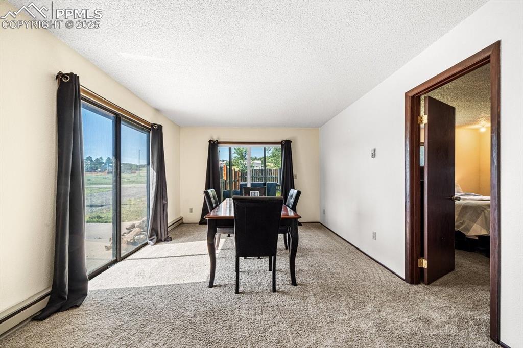 Image 12 of 38: Dining area with a textured ceiling, light carpet, and a baseboard radiator