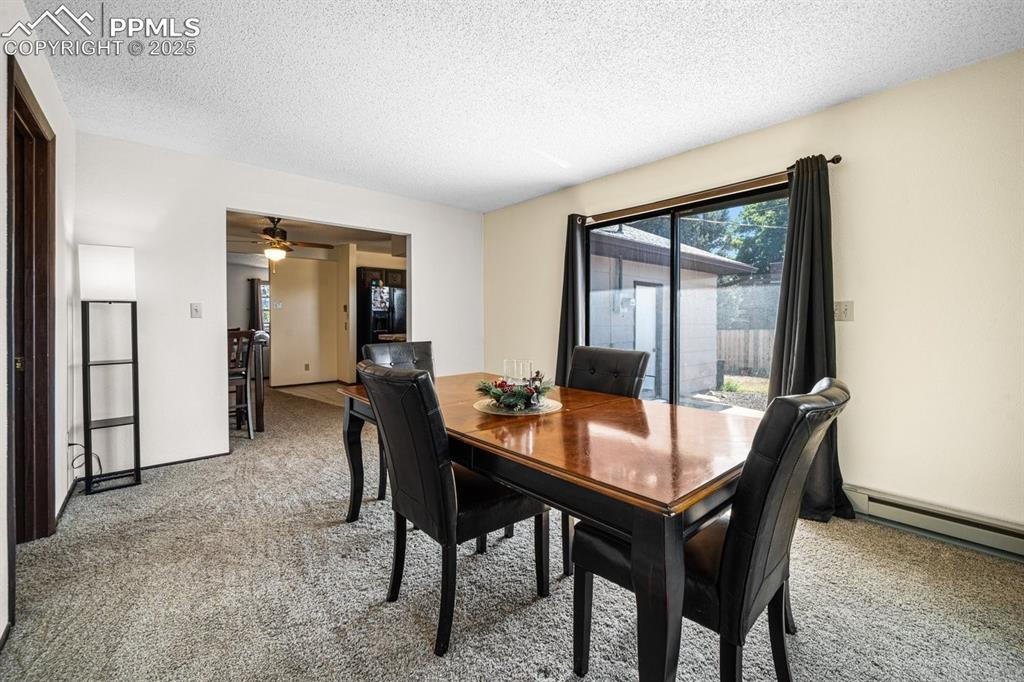 Image 14 of 38: Dining space featuring light carpet, a textured ceiling, a baseboard heatin