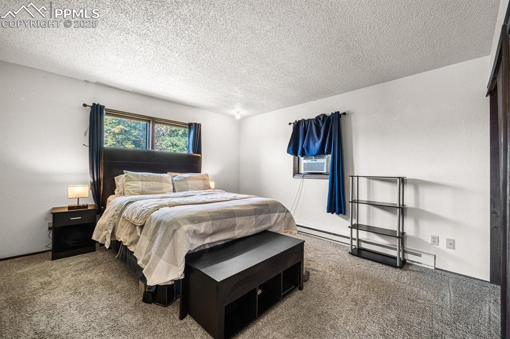 Image 15 of 38: Carpeted bedroom featuring a baseboard heating unit, a textured ceiling, an