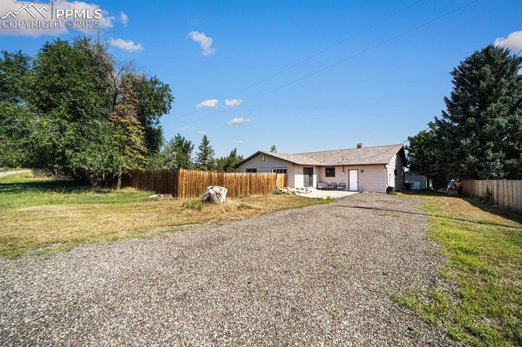 Image 29 of 38: Single story home with a patio area, a chimney, and gravel driveway
