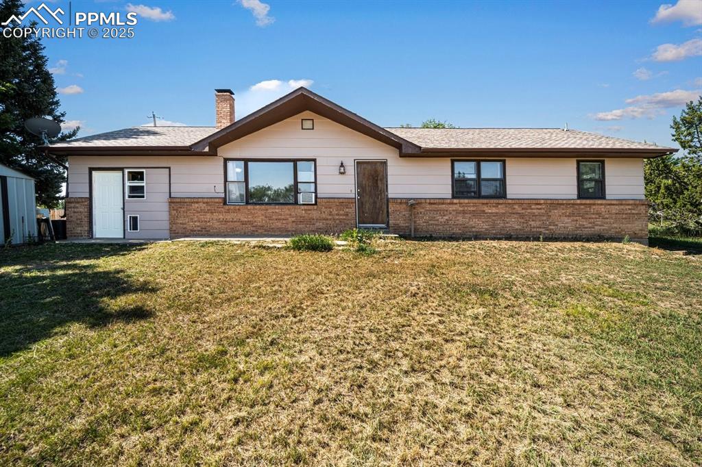 Image 3 of 38: Ranch-style home with brick siding, a front lawn, and a chimney