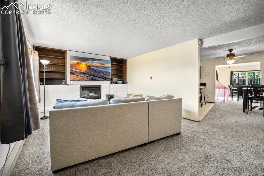 Image 5 of 38: Living room featuring carpet flooring, a textured ceiling, ceiling fan, and