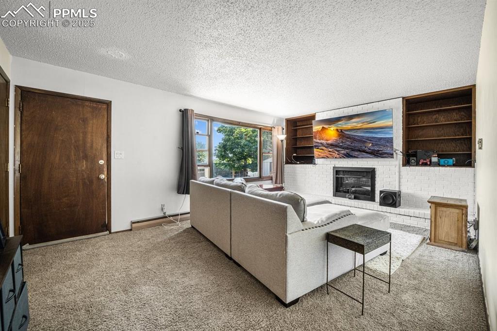Image 7 of 38: Carpeted living room featuring a textured ceiling, built in features, baseb
