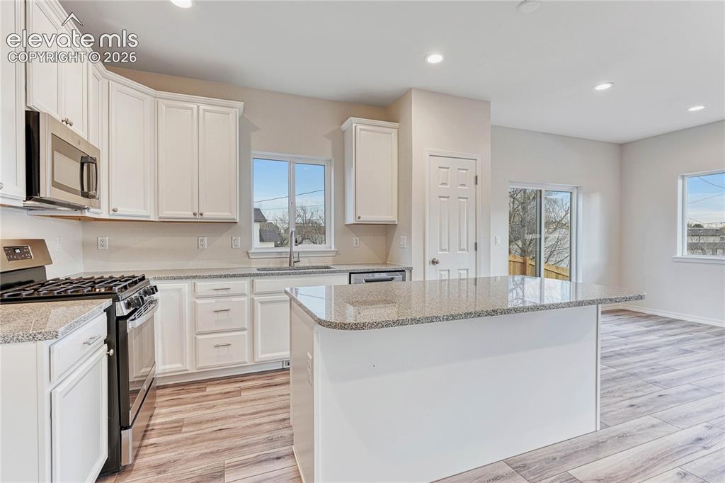 Image 5 of 28: 42" extended height cabinetry, stone countertops, island, panty, and stainl