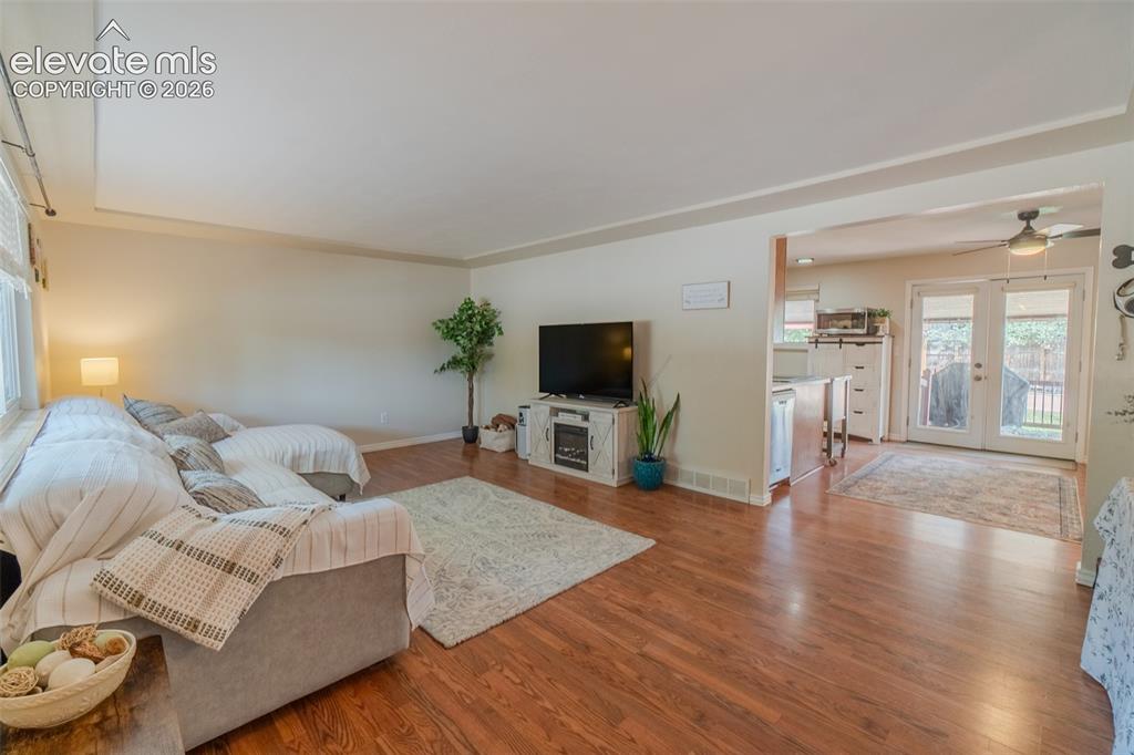 Image 12 of 46: Inviting living area featuring rich wood-finish flooring, a large window wi