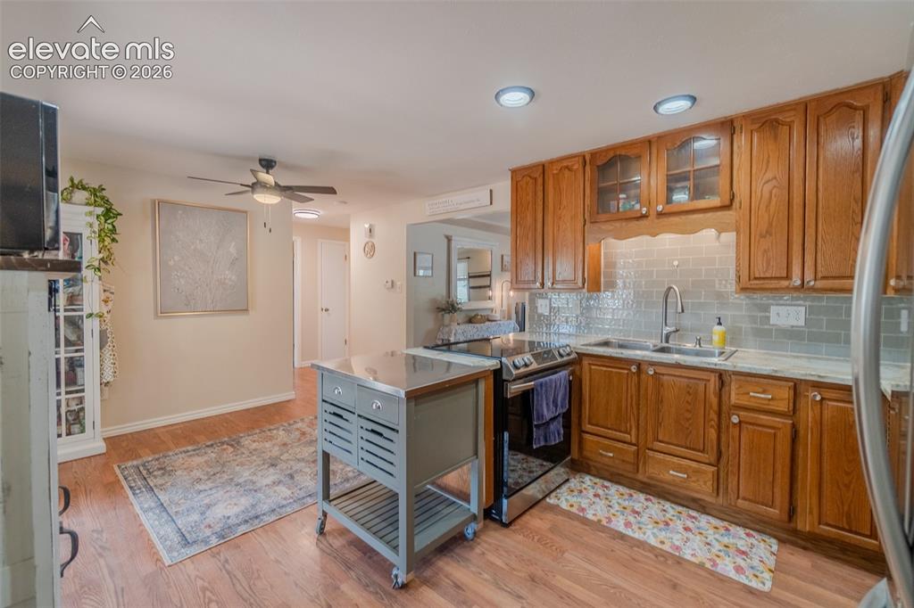 Image 14 of 46: Kitchen featuring wood-finish cabinetry, light-toned countertops, and a til