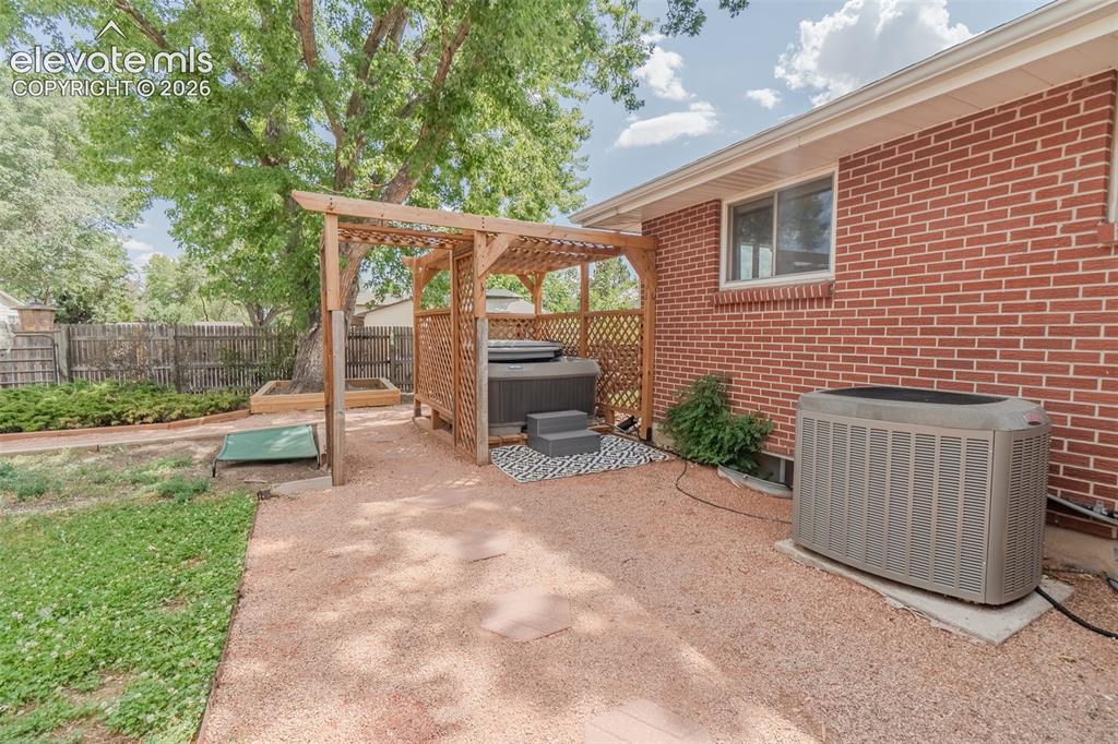 Image 41 of 46: Outdoor hot tub enclosure featuring a wooden lattice pergola, brick exterio