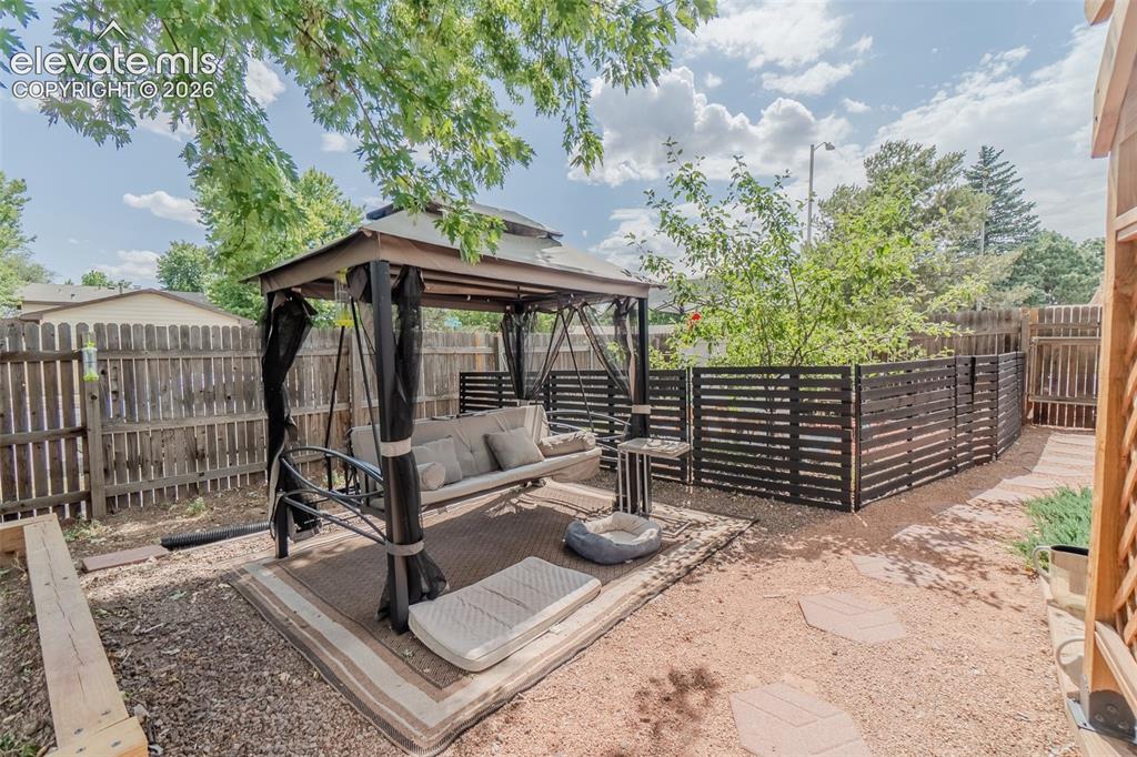 Image 45 of 46: Expansive backyard featuring a large tree, a privacy fence, and a gravel gr