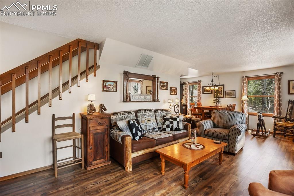 Image 10 of 49: Living room featuring a textured ceiling, dark wood finished floors, stairw