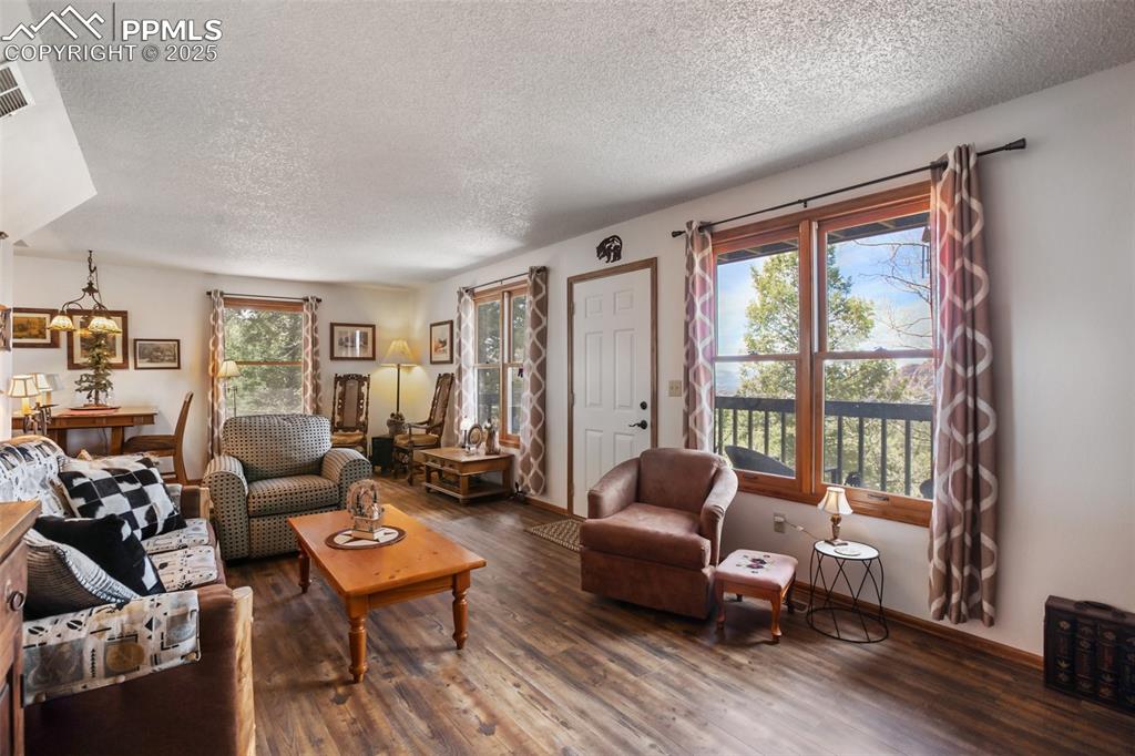 Image 11 of 49: Living room with a textured ceiling, wood finished floors, and baseboards