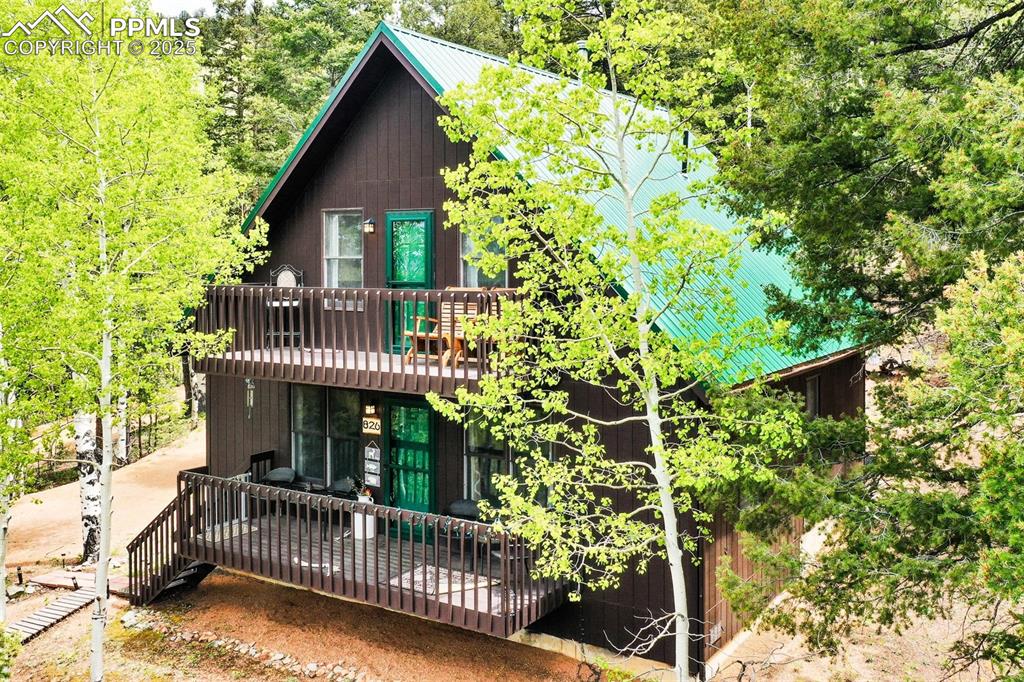 Image 2 of 49: View of front of home with a wooden deck and metal roof