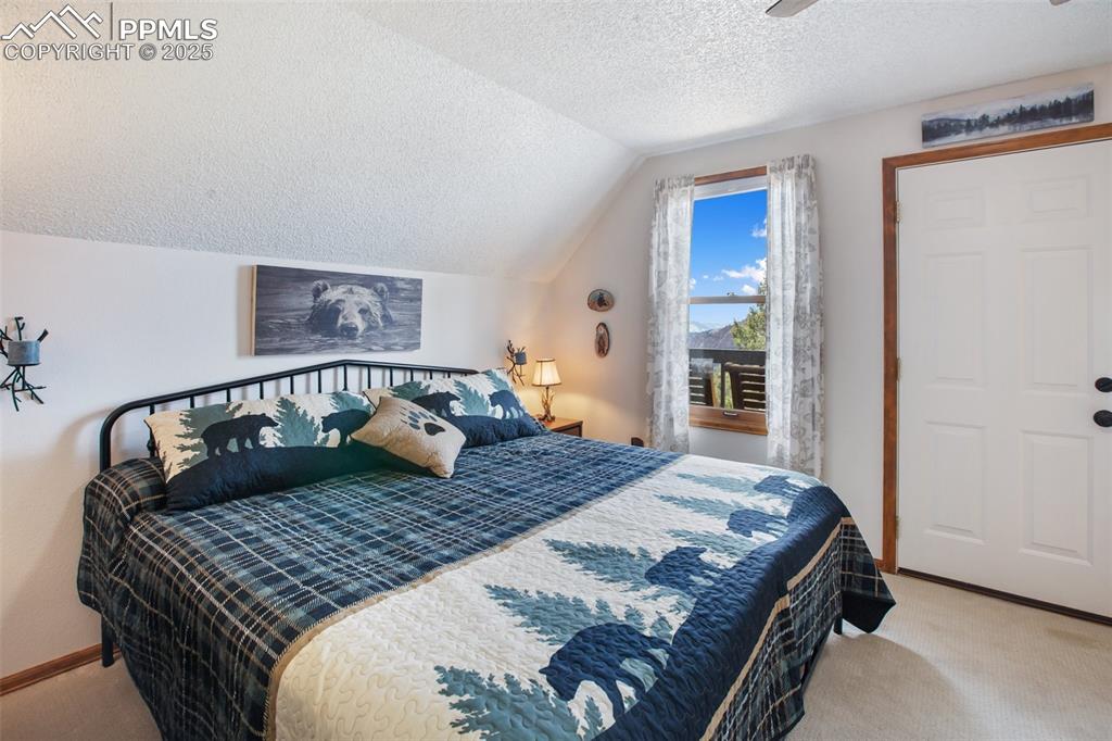 Image 20 of 49: Bedroom featuring carpet flooring, vaulted ceiling, a textured ceiling, and