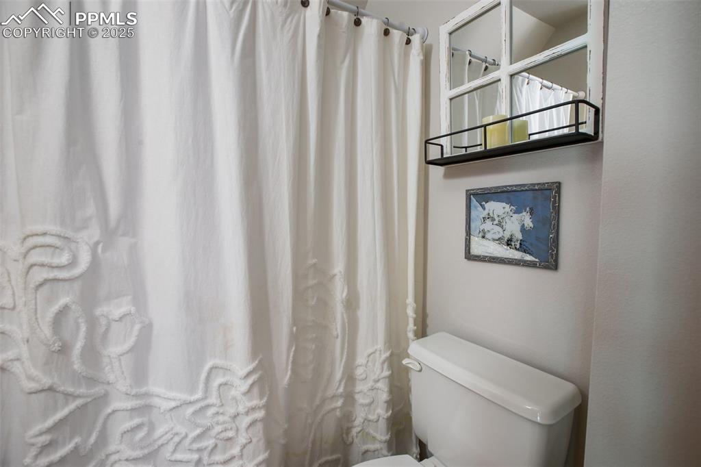 Image 28 of 49: Bathroom featuring toilet and a shower with curtain