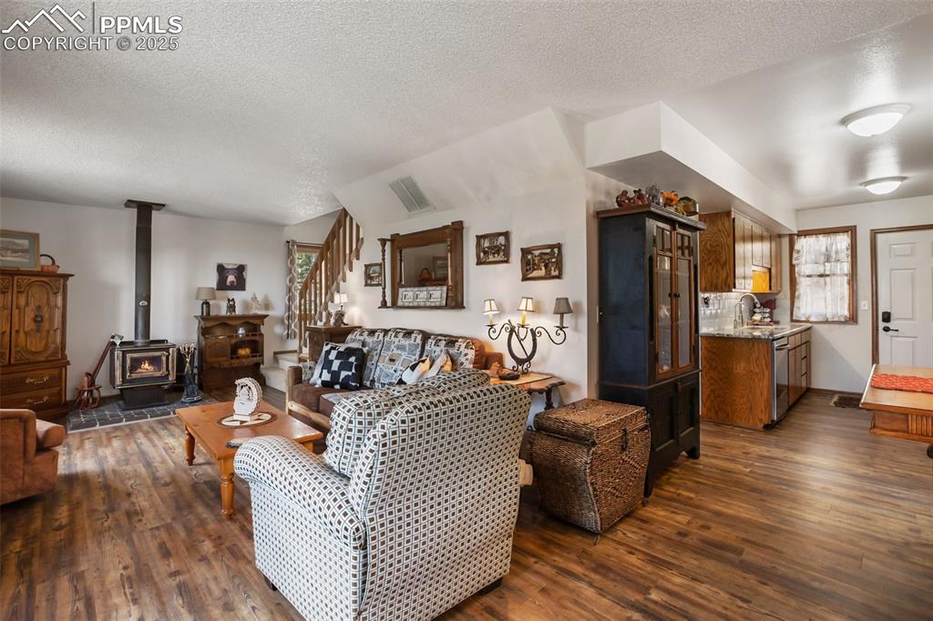 Image 4 of 49: Living room featuring dark wood-type flooring, a textured ceiling, a wood s