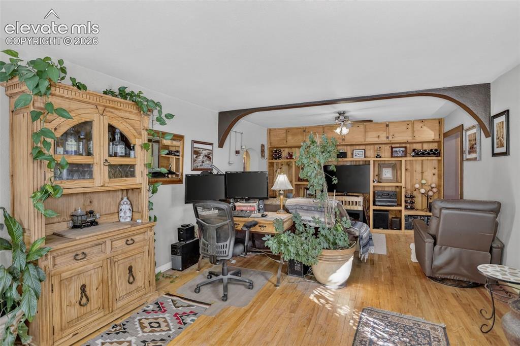 Image 15 of 25: Hardwood flooring, arched entryway, built-in shelving, wood paneling, and c