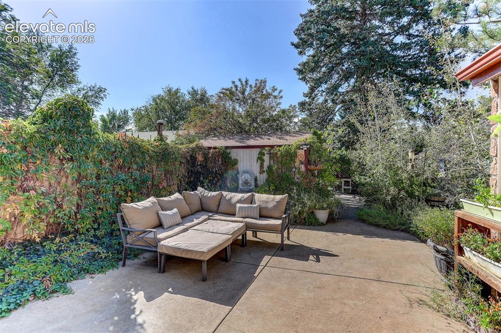 Image 17 of 25: Paved patio area, established perimeter landscaping, mature trees
