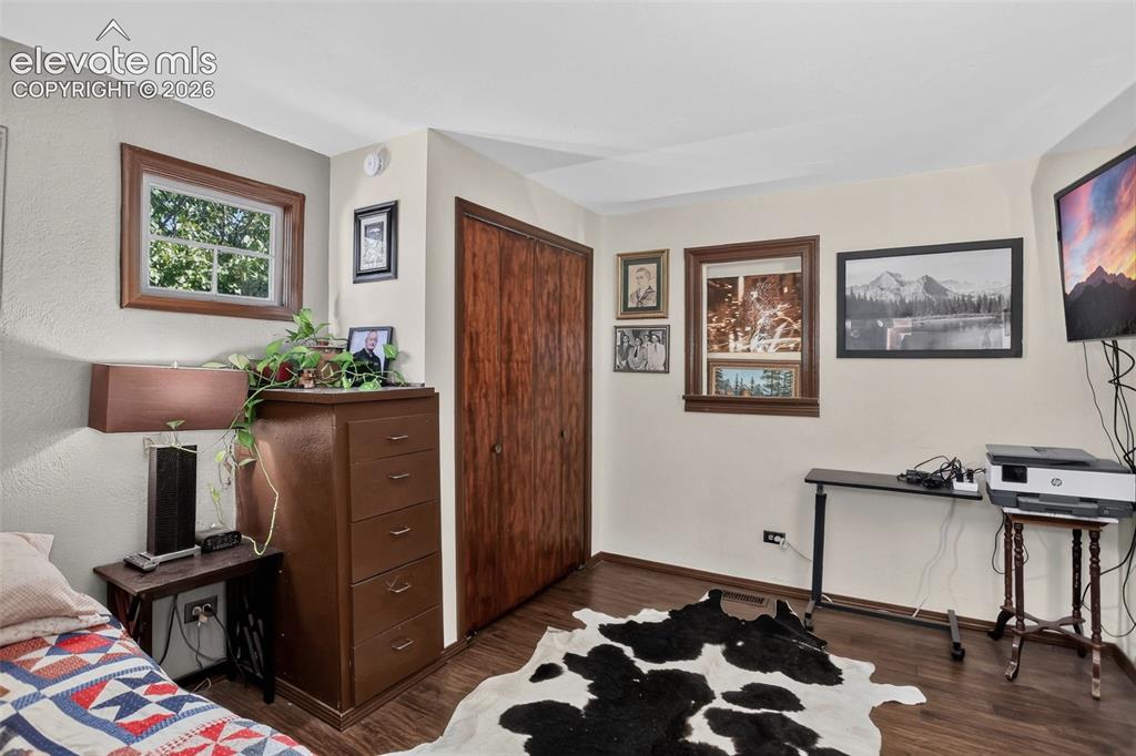 Image 20 of 25: Wood-finish flooring with a smooth texture, two windows with wood trim, a b