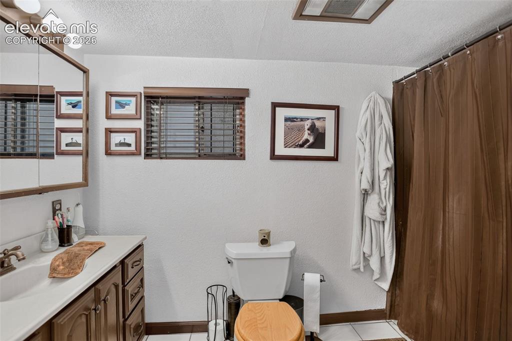 Image 22 of 25: Bathroom featuring a vanity with a white countertop and wood-finish cabinet