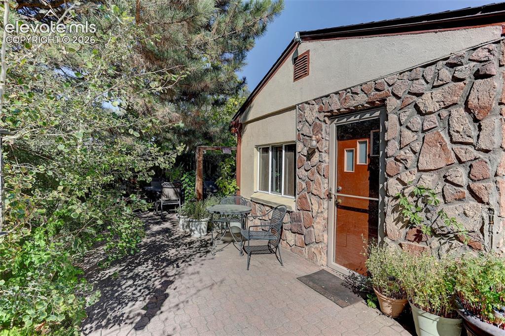 Image 7 of 25: Patio area featuring interlocking paver stones, a stone-clad exterior, and 