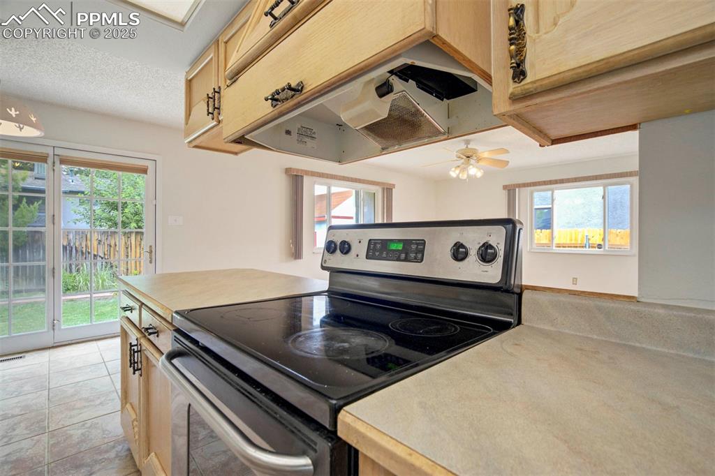 Image 10 of 45: Kitchen with stainless steel range with electric cooktop, light countertops