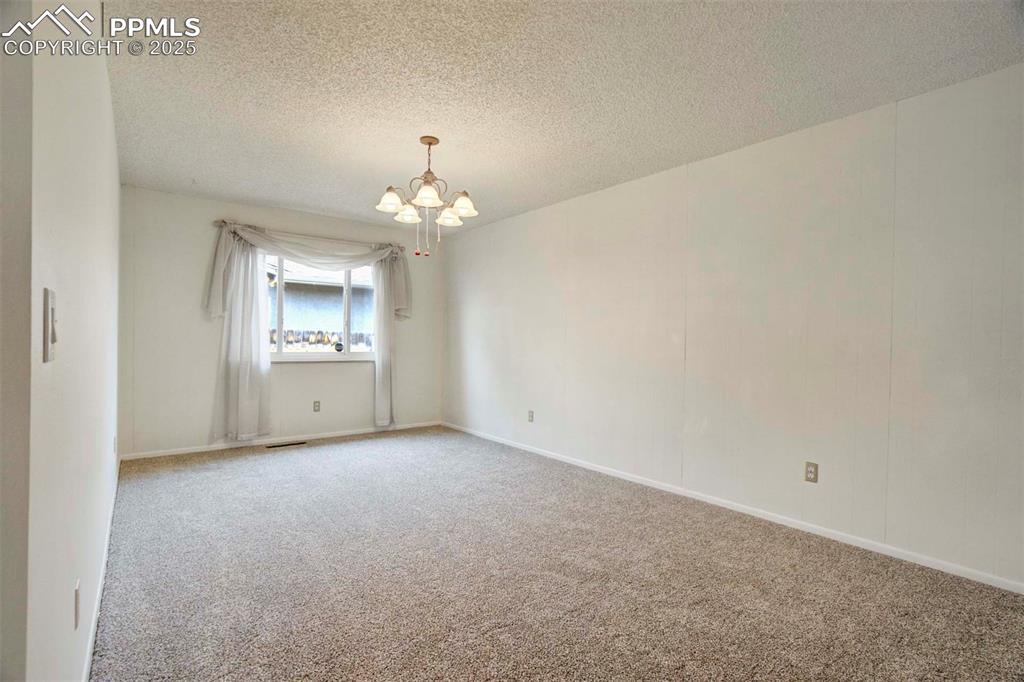 Image 12 of 45: Family room with carpet flooring, a chandelier, and a textured ceiling