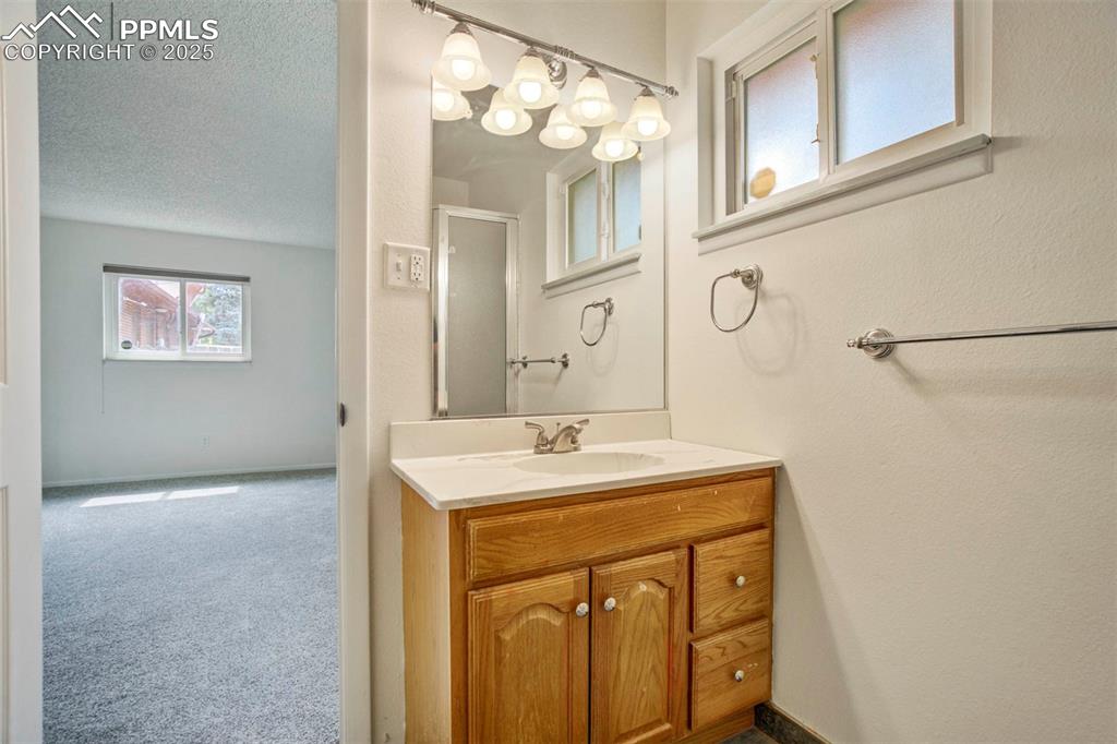 Image 18 of 45: Bathroom featuring vanity, a shower stall, and a textured ceiling
