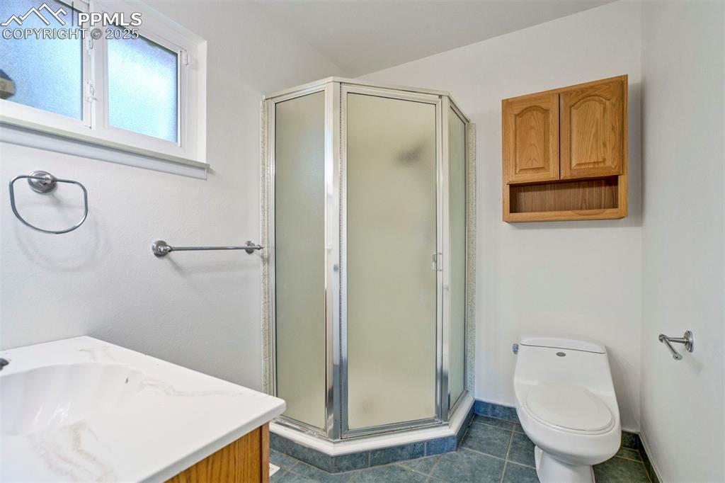 Image 19 of 45: 3/4 bath featuring vanity, a shower stall, and dark tile patterned floors