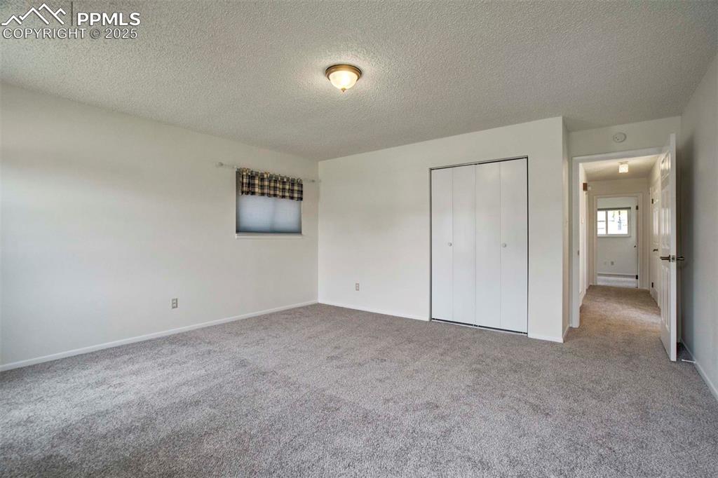 Image 21 of 45: Bedroom with a textured ceiling, light colored carpet, and a closet