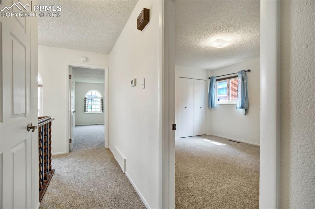 Image 23 of 45: Hallway featuring light colored carpet and a textured ceiling