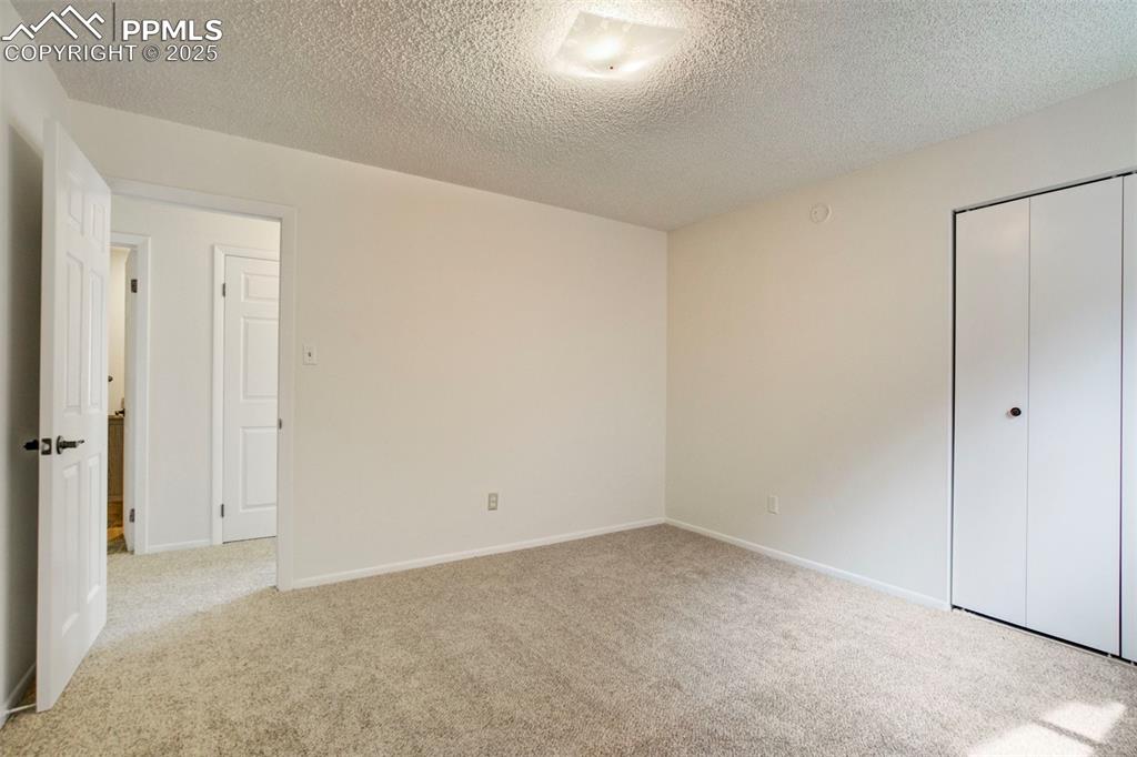 Image 25 of 45: Bedroom with light carpet, a textured ceiling, and a closet
