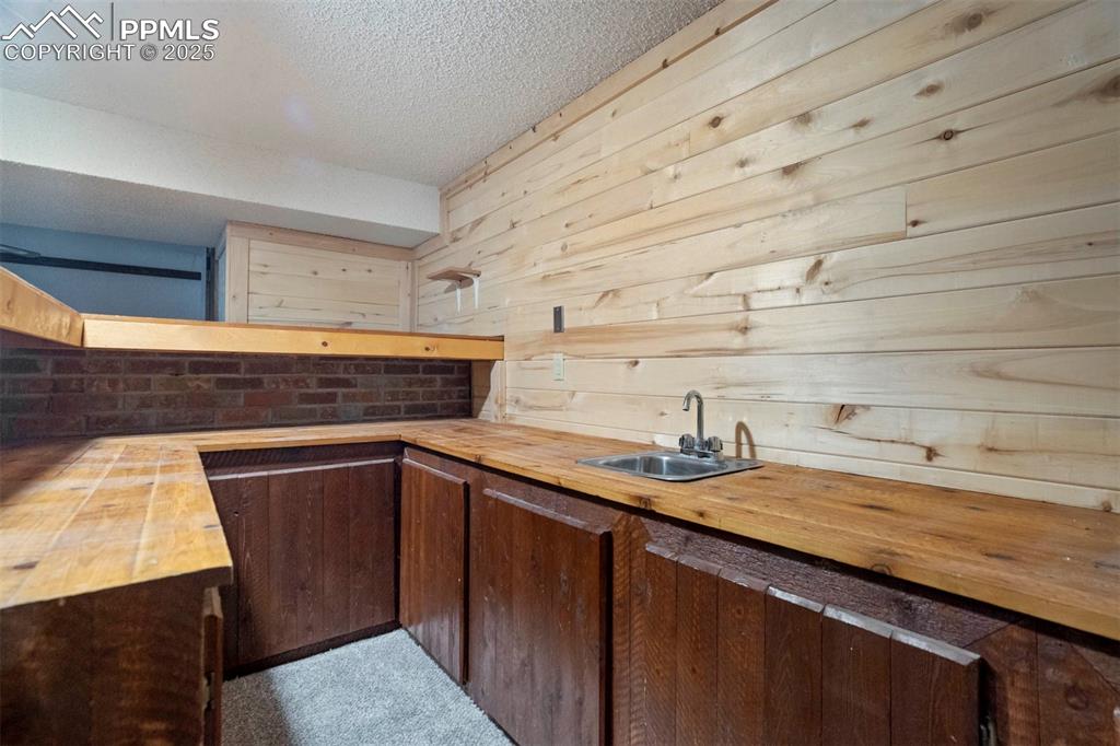 Image 35 of 45: Bar area with butcher block countertops, dark brown cabinets, a textured ce