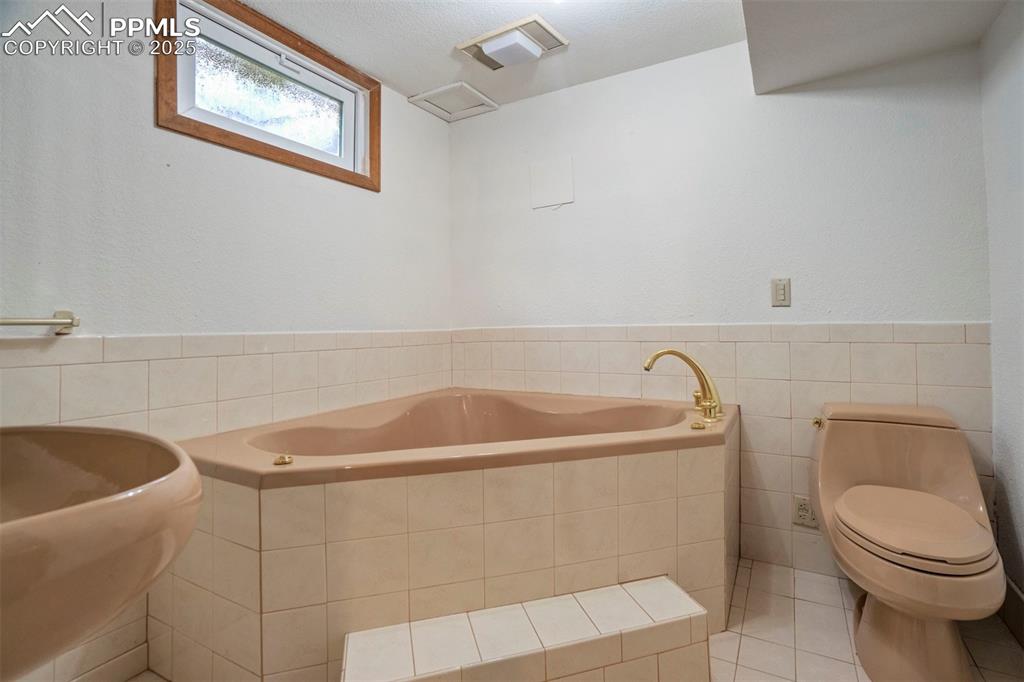 Image 39 of 45: Bathroom featuring tile walls, a garden tub, tile patterned floors, and wai