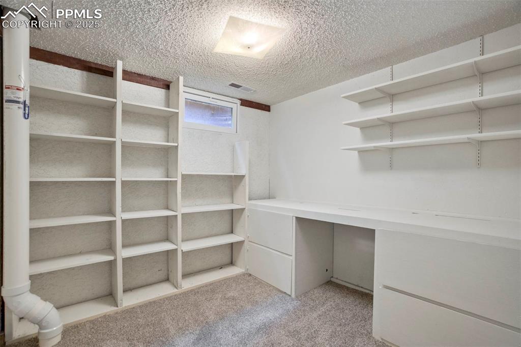 Image 40 of 45: Spacious office with light carpet and built-in shelves and desk