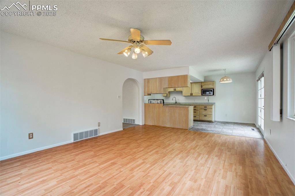 Image 5 of 45: Living room featuring arched walkways, a textured ceiling, light wood-style