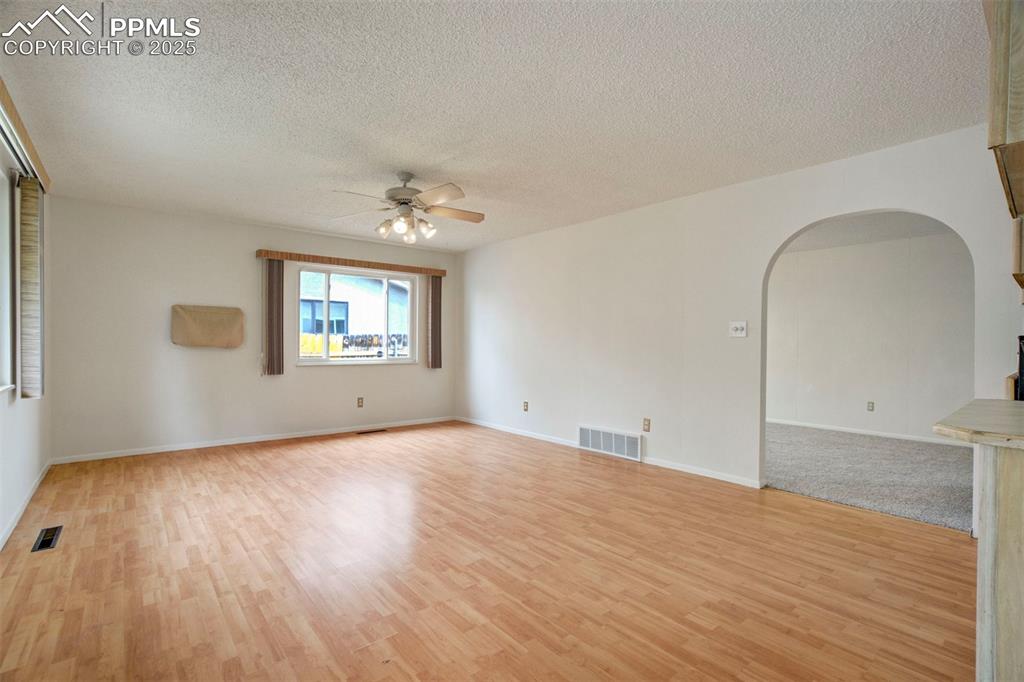 Image 6 of 45: Living room with arched walkways, a textured ceiling, light wood-style floo